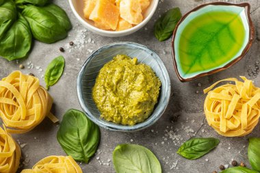 Popüler İtalyan pesto sosu. Bir tabak ile bir masada makarna pişirme kavramı, malzemeler ve baharatlar. Vejeteryan yemekleri. Üst görünüm, yakın çekim.