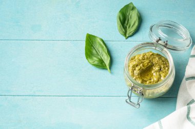 Popüler İtalyan pesto sosu. Pişirme malzemeleri ve baharatlar. Vejeteryan yemekleri. Üst görünüm, yakın çekim, kopya alanı. Mavi arka plan.