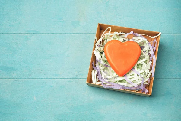 Soap in the form of a heart in a gift box on a blue background, top view, copy space. Natural handmade soap.