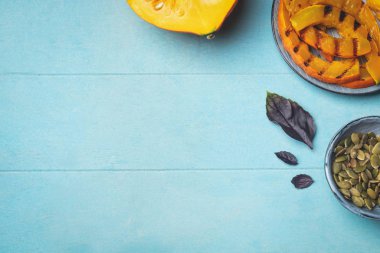 Çiğ kabak bir parça, ızgara, kabak çekirdeği ve fesleğen yaprakları dilimleri. Bir çerçeve şeklinde Görüntüler, kopya alanı. Mavi ahşap arka plan.