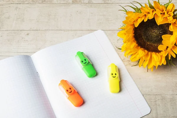 Sunflowers, copybook and markers on a white wooden background. Back to school concept. Copy space.