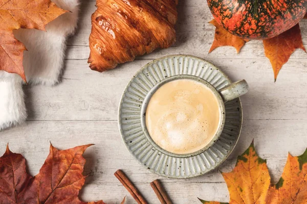 Coffee, croissant, pumpkin, white fluffy sweater on a white background and maple autumn leaves.