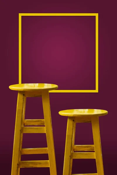 Yellow bar stool with magenta background and copy space frame on the wal