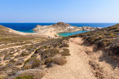 Agios Sostis plaj. Sandy beach uçurumun kenarına Agios Sostis Kilisesi ile. Kiklad Adaları, Yunanistan