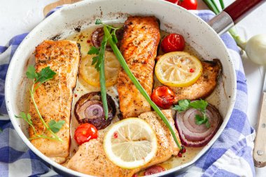 Soğan ile bir tavada kızarmış somon, limon ve kiraz domates