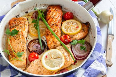 Soğan ile bir tavada kızarmış somon, limon ve kiraz domates