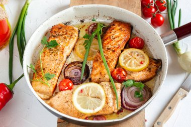 Soğan ile bir tavada kızarmış somon, limon ve kiraz domates