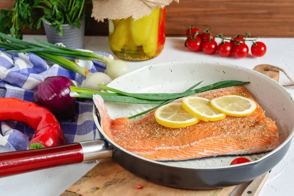 Fresh salmon in a pan with lemon and cherry tomatoes ready to cooking.