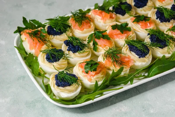 Stuffed eggs with salmon and caviar decorated by parsley and dill. Party food