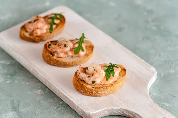 Bruschetta sandwiches with shrimps, creamy sauce and rocket salad. — Stock Photo, Image