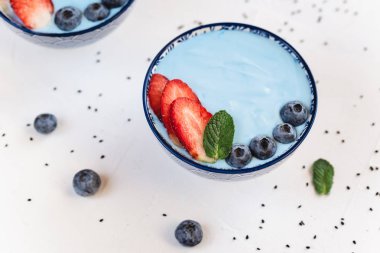 Mavi spirulina tozu, çilek ve yaban mersini ile yapılan mavi yoğurt güler yüzlü.