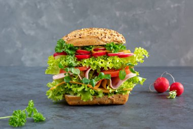 Jambon, peynir ve taze sebze karanlık bir tahta üzerinde büyük sandviç. Kahvaltı konsepti.