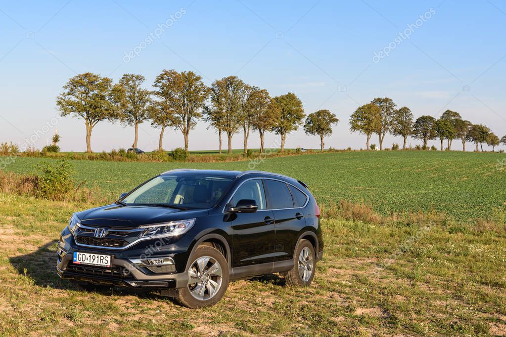 PUCK, POLAND - September 18, 2018: Honda CR-V car parked in a field on a country road next to a wind farm
