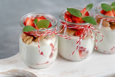 Yoğurtlu taze çilek ve bir kavanoz içinde ufalanmış bisküvi.