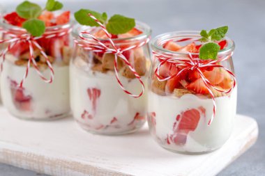 Yoğurtlu taze çilek ve bir kavanoz içinde ufalanmış bisküvi.