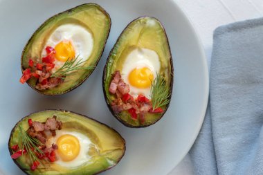 Avokado bacon, kırmızı pul biber ve dereotu ile bıldırcın yumurtası pişmiş.