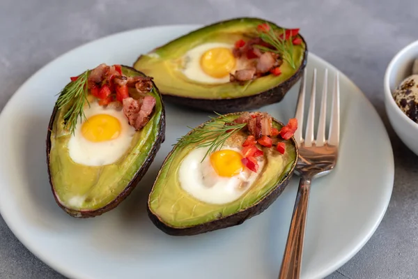 Quail eggs baked in avocado with bacon, red paprika and dill.