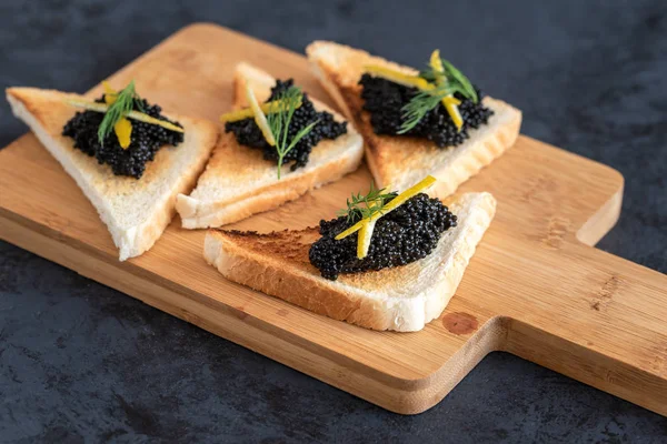Pan tostado de aperitivo con caviar negro decorado con píldora de limón y eneldo — Foto de Stock