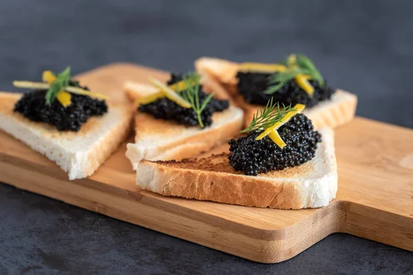 Pan tostado de aperitivo con caviar negro decorado con píldora de limón y eneldo — Foto de Stock