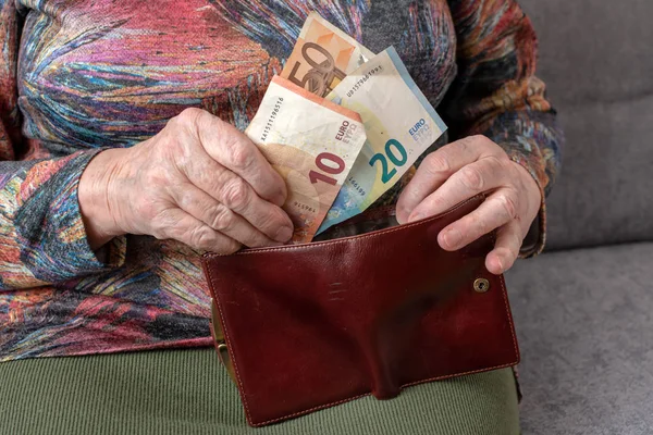 Τα χέρια της μια ηλικιωμένη συνταξιούχος κρατώντας δερμάτινο πορτοφόλι με χρήματα νόμισμα ευρώ. Έννοια της οικονομική ασφάλεια στα γεράματα. — Φωτογραφία Αρχείου