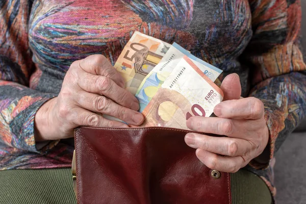 Mãos de um idoso pensionista segurando carteira de couro com dinheiro em euros. Conceito de segurança financeira na velhice . — Fotografia de Stock