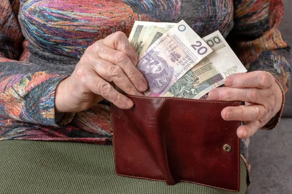 De handen van een bejaarde gepensioneerde lederen portemonnee met Pools munt geld te houden. Concept van financiële zekerheid in de ouderdom. — Stockfoto