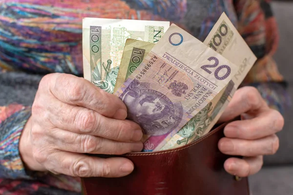 Mãos de um pensionista idoso segurando carteira de couro com dinheiro polonês moeda. Conceito de segurança financeira na velhice . — Fotografia de Stock