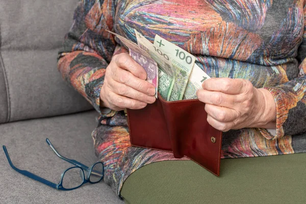 Mãos de um pensionista idoso segurando carteira de couro com dinheiro polonês moeda. Conceito de segurança financeira na velhice . — Fotografia de Stock