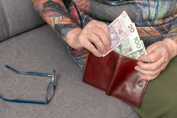 Manos de un anciano pensionista con billetera de cuero con dinero de moneda polaca. Concepto de seguridad financiera en la vejez . — Foto de Stock