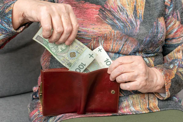Rukou starší důchodce drží kožená peněženka s polská měna (peníze). Koncept finančního zajištění ve stáří. — Stock fotografie