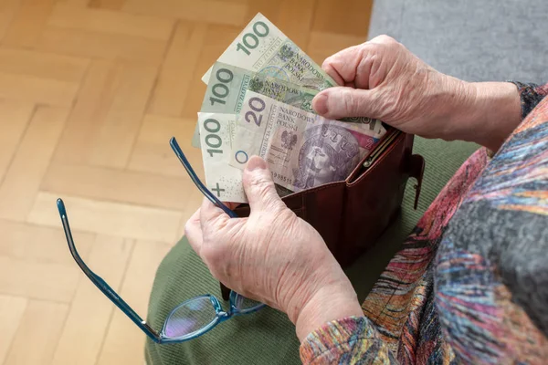 Mãos de um pensionista idoso segurando carteira de couro com dinheiro polonês moeda. Conceito de segurança financeira na velhice . — Fotografia de Stock