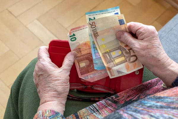 Mãos de um idoso pensionista segurando carteira de couro com dinheiro em euros. Conceito de segurança financeira na velhice . — Fotografia de Stock