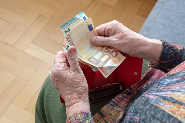 De handen van een bejaarde gepensioneerde lederen portemonnee met euro munt geld te houden. Concept van financiële zekerheid in de ouderdom. — Stockfoto