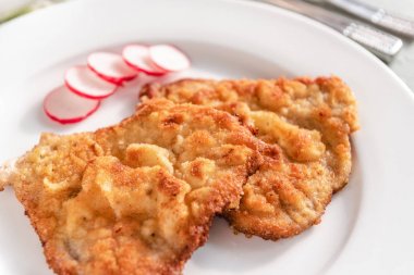 Beyaz tabakta servis edilen ekmek kırıntılarında kızarmış domuz pirzolası