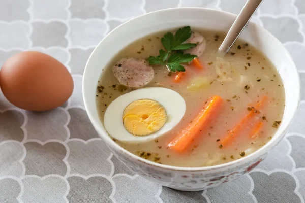 Traditional Polish soup Zurek with white sausage and egg.