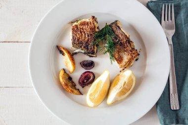 Izgara dorado balık limon ve kırmızı soğan ile servis.