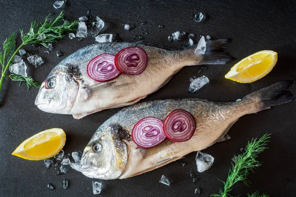 Świeże niegotowane Dorado ryby z lodu i warzyw serwowane na czarnej płycie. — Zdjęcie stockowe