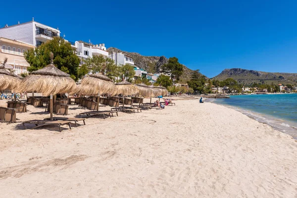 Mallorca, İspanya - 6 Mayıs 2019: Mallorca'nın kuzeybatısında popüler bir aile tatil beldesi olan Port de Pollenca'da (Puerto Pollensa) sahilde saman şemsiyeler. İspanya