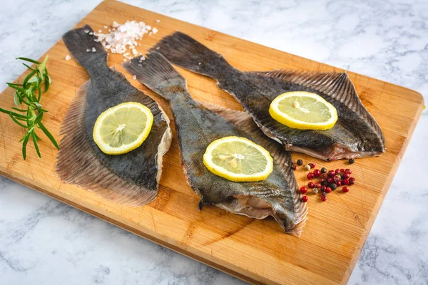 Świeże niegotowane ryby flątwy z przyprawami na drewnianej płycie — Zdjęcie stockowe