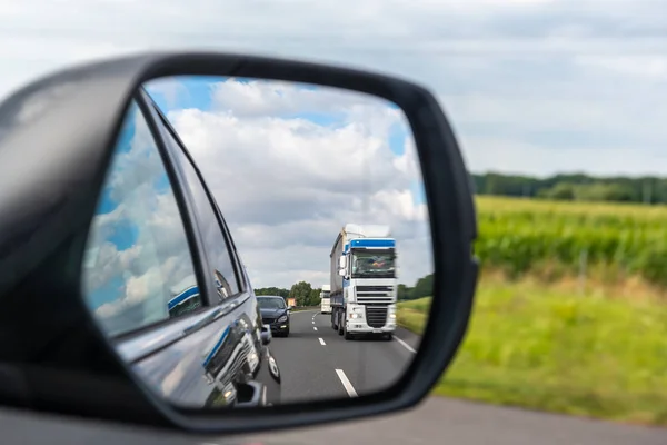 Asfalt weg met vrachtwagen weerspiegeld in auto spiegel. — Stockfoto