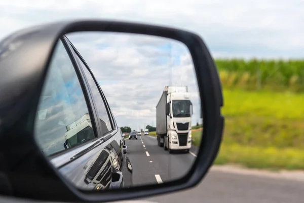 Estrada de asfalto com caminhão refletida no espelho do carro . — Fotografia de Stock