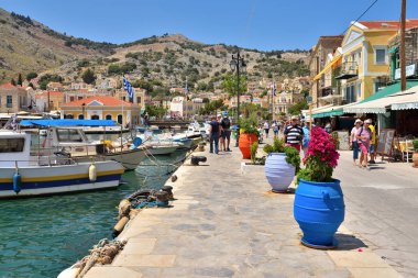 Symi, Yunanistan - 15 Mayıs 2018: Deniz boyunca gezinti yolu üzerinde çiçekler le colorful tencere. Symi island, Yunanistan