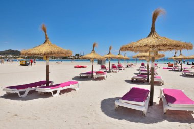 Mallorca, İspanya - 11 Mayıs 2019: Mallorca, İspanya'daki Playa de Alcudia plajında şemsiyeli şezlonglar