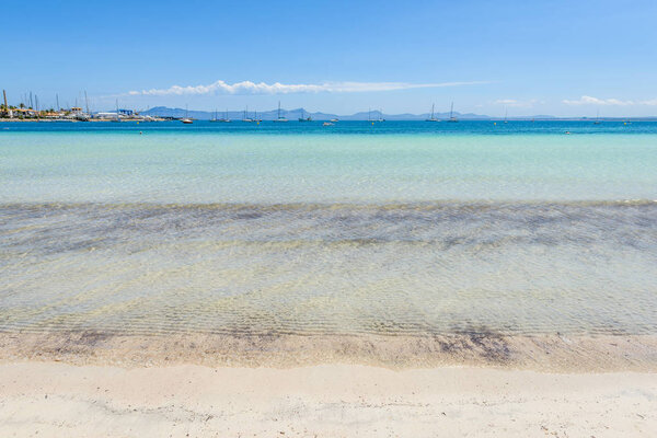 Shallow and crystal waters of Playa de Alcudia beach in northern Mallorca, Spain