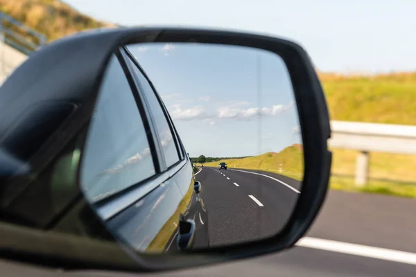 Asphaltstraße mit Fahrzeug, das sich im Autospiegel spiegelt. Konzept des sicheren Fahrens. — Stockfoto