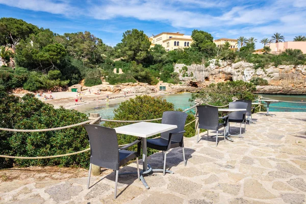 Mallorca, Hiszpania-9 maja 2019: Stoły z krzesłami z widokiem na plażę Cala Ferrera, popularnym miejscem rodzinnym w południowo-wschodniej części Majorki. Hiszpania — Zdjęcie stockowe