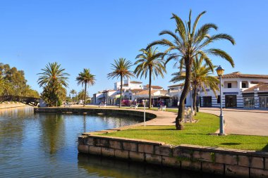 Mallorca, İspanya - 11 Mayıs 2019: Mallorca'daki Alcudia şehrinde bir kanal boyunca büyüyen palmiye ağaçları