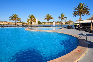 Mallorca, İspanya - 11 Mayıs 2019: Alcudia, Mallorca'da palmiye ağaçlarına bakan yüzme havuzu
