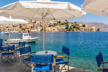 SYMI, GREECE - 15 Mayıs 2018: Yunanistan 'daki Symi adasında deniz körfezi manzaralı kıyı restoranı.