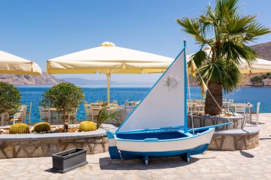 SYMI, GREECE - 15 Mayıs 2018: Yunanistan 'daki Symi adasında deniz körfezi manzaralı kıyı restoranı.